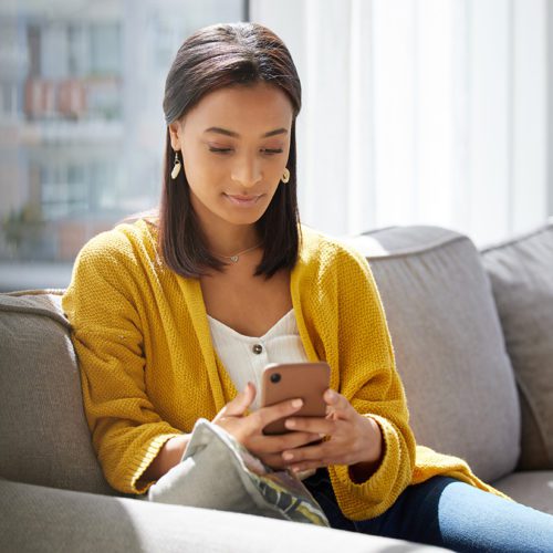 Phones have many uses. Shot of a young woman using a phone at homae