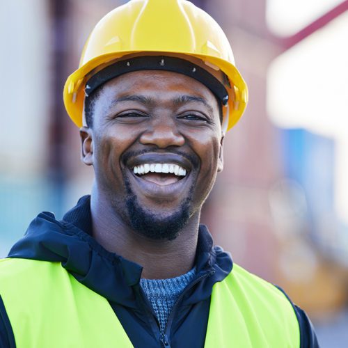 Portrait, logistics and black man smile with helmet or hard hat at shipyard and confident at work. .